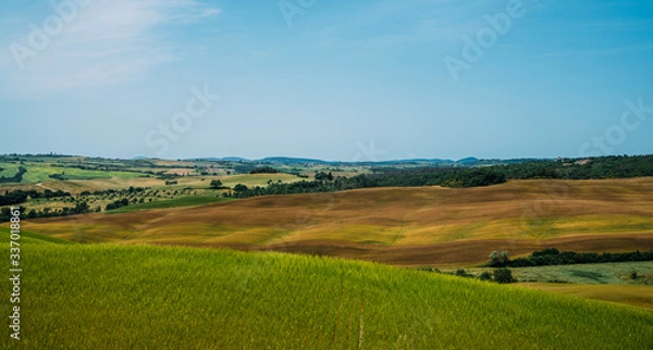 Fototapeta Tuscany village landscape on a sun day, Italy. Beautiful green hils and rural fields. Agricultural area with fields and cypresses. Vintage tone filter effect with noise and grain.