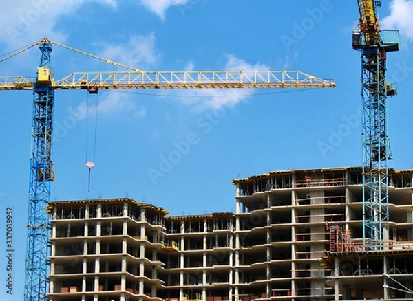 Fototapeta Two self-erection cranes near building. Construction site background.