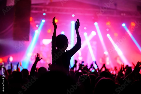 Fototapeta a silhouette of an applauding crowd in front of a stage in pink light. banner for a music festival. poster of the upcoming show.