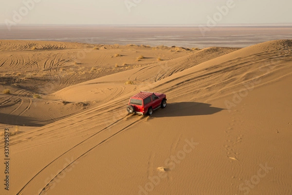 Fototapeta A beautiful view of the red car in the desert