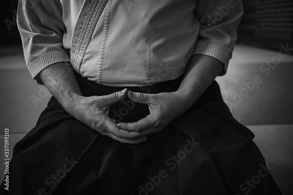 Fototapeta Man in kimono is practicing meditation in martial arts dojo