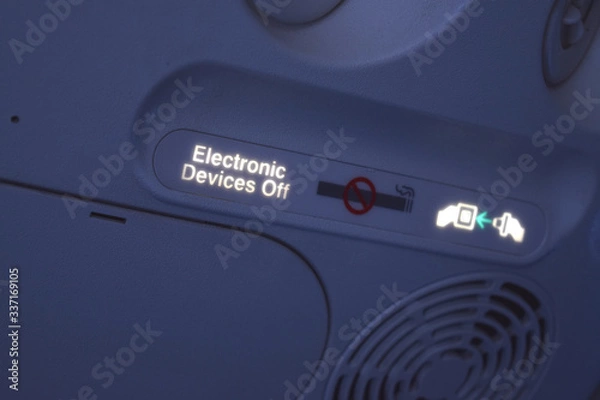 Fototapeta Electronic sign on airplane.  Fasten your seat belt, no smoking and turn off electronic devices. Safety warnings during flight