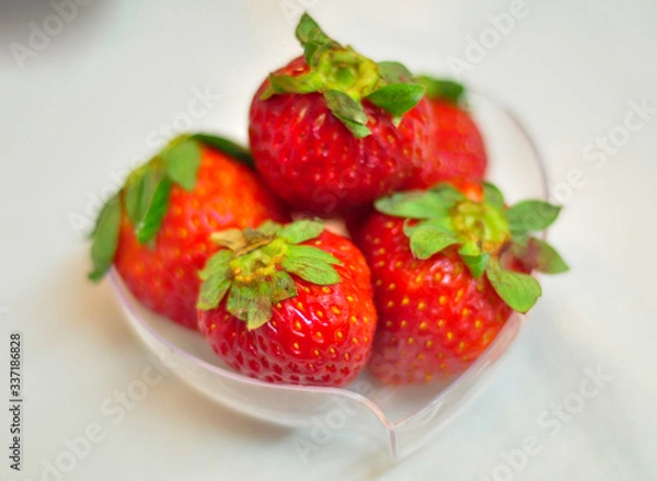 Fototapeta Fresh strawberries in a small heart-shaped plastic container