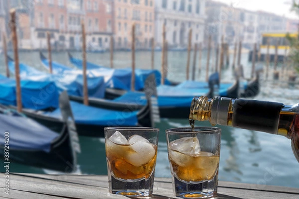 Fototapeta Drink for two in front of the Grand Canal of Venice - Romantic holiday for couples. Two glasses of liqueur with ice on a sunny morning.