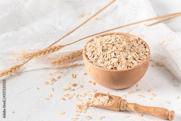 Obraz Raw oatmeal flakes on light background