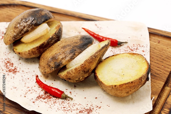 Fototapeta Sliced and fried potaes lined on a wooden board with lard inside. Potatoes decorated of red pepper.