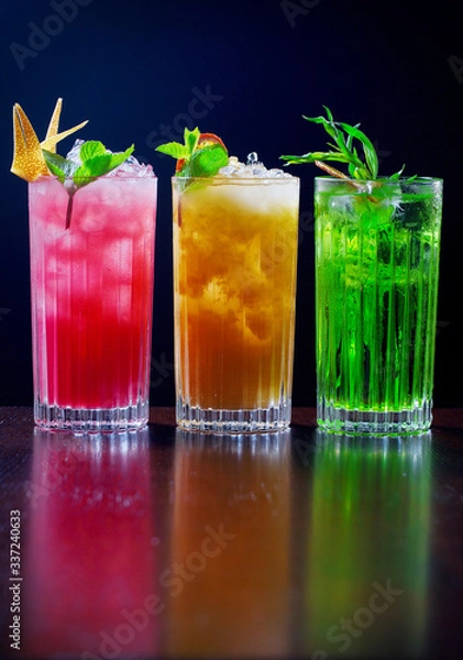 Fototapeta  Lemonades with ice stand on a table on a black background and decorated with mint, lemon and limes.
