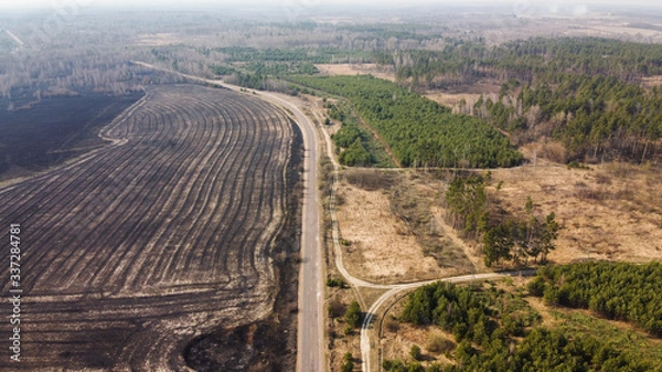 Fototapeta Forest and field fire. Dry grass burns, natural disaster. Aerial view. After the fire
