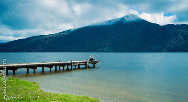 Obraz Kaniere Lake, New Zealand, October 7, 2019: Beautiful panorama of a loving couple sitting at the end of the pier admiring the landscape