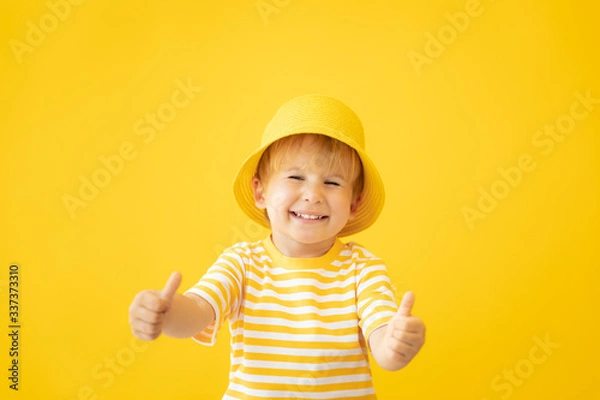 Obraz Portrait of happy child against yellow background. Summer vacation concept