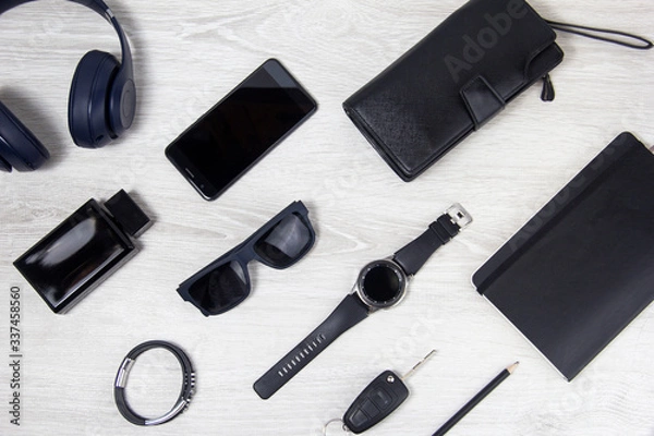 Fototapeta Background men's accessories lie on a wooden background. Black glasses, watch, notebook, wallet are on a light background. Objects close-up, top view