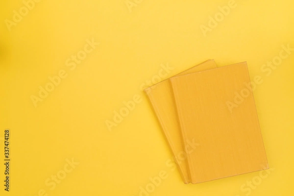Fototapeta Two yellow books with blank cover on a yellow background. Hard cover. Top view. Copy space