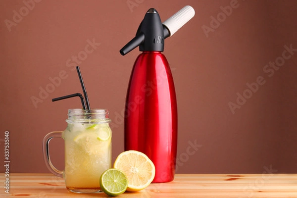 Fototapeta lime and lemon cocktail. non alcoholic citrus summer drinks with citrus on wooden table. Siphon, a device for making soda.