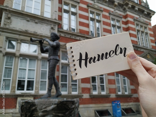 Fototapeta The Pied Piper of Hameln is the most famous German legend.This photo shows a statue in his hometown Hamelin, Lower Saxony, Germany. View with calligraphic inscription "Hameln". Mobile photography.