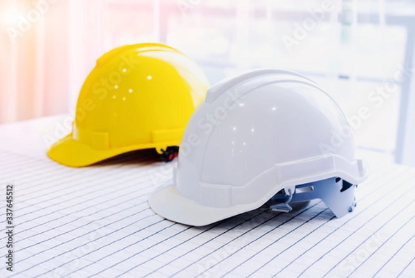 Fototapeta Helmet placed on a white table, White and  yellow hard safety helmet hat for safety project of workman as engineer or worker, Safety concept.
