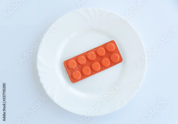 Fototapeta Orange blister with pills on a white plate. Flat lay. Isolated on white background