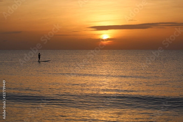 Fototapeta Mężczyzna w sylwetce pływa na desce SUP, gdy słońce wschodzi nad Oceanem Atlantyckim w Delray Beach na Florydzie.