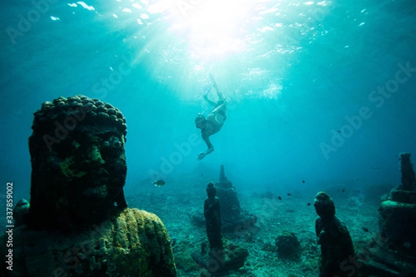 Fototapeta Scuba diver swimming underwater near Buddha statues