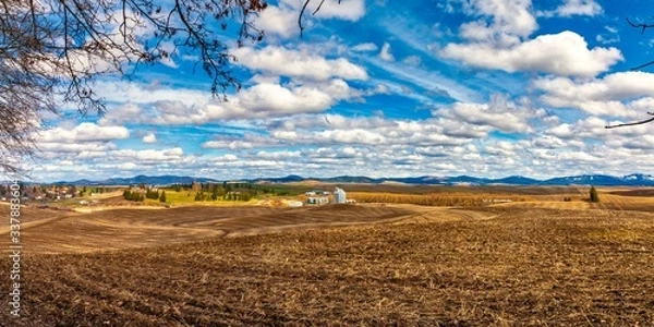 Fototapeta Farm land of rolling hills and grain silo in the distance