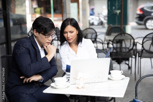 Fototapeta Asian business men and business woman working with laptop computer at a co-working space, Coffee shop. Communication and Brainstorm