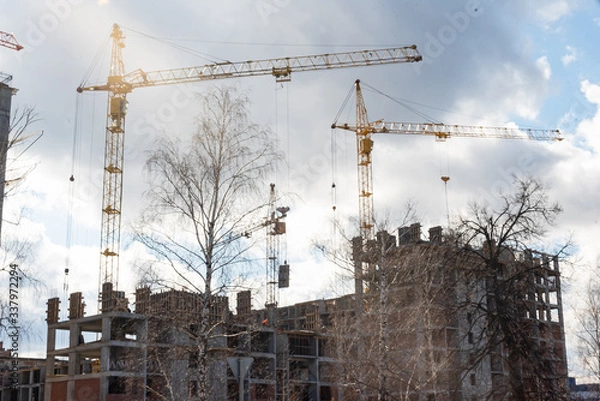 Fototapeta Tower building cranes build new multi-storey houses from monolithic frame and monolithic brick structure