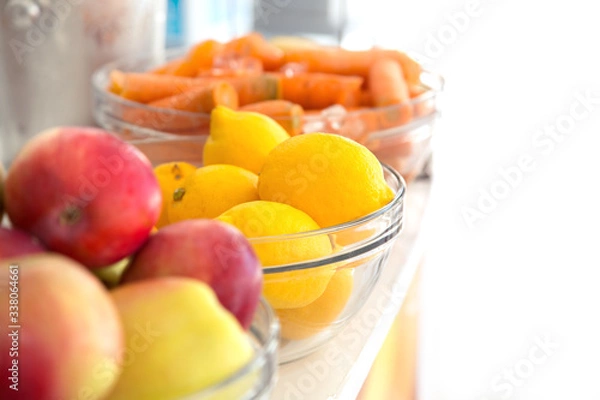 Fototapeta Fresh lemons. Yellow lemons with apple and carrots in the background