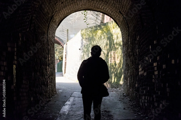 Fototapeta Light at the end of the tunnel. Silhouette of people in an underground passage