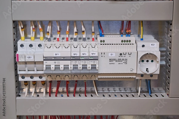 Fototapeta Fuse holder, two circuit breakers, power supply and socket in the electrical Cabinet. The wires and cables are connected to the electrical equipment and laid in the cable channel.