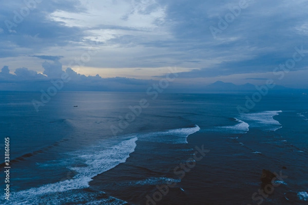 Fototapeta Beautiful blue sunset on the ocean with big waves and cliffs and cliffs. Bali island with its tropical and exotic nature. Sunrise over the sea and ocean. Phantom blue in sunset