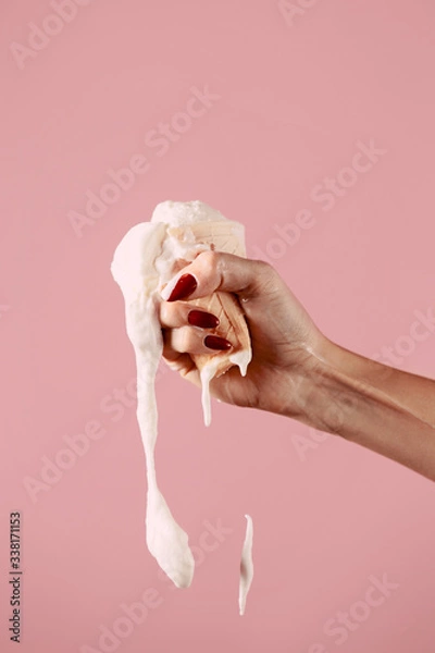 Fototapeta ice cream is melting in hand, fist squeezes ice cream on a pink background