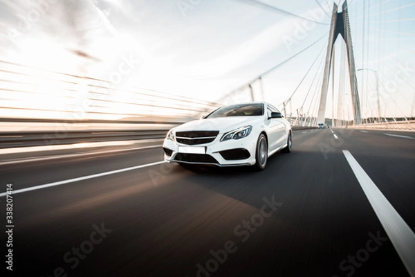 Obraz White business class sedan car driving on the highway over the bridge in the daytime