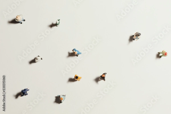 Fototapeta Top view of people (miniature toys) with long shadows keep distance away in public during sunrise or sunset.Social distancing / COVID-19 coronavirus outbreak spreading concept.