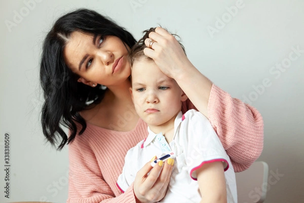 Fototapeta mom measures the temperature of the child, the boy got the virus