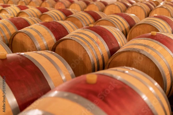 Fototapeta Wine barrels stacked in the old cellar of the winery. (Selective focus)