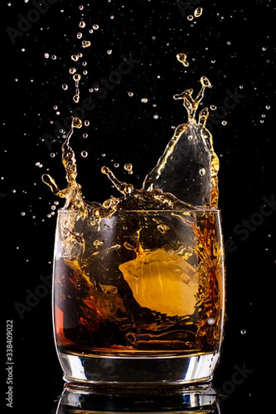 Fototapeta Splash in a glass from falling ice on a black background