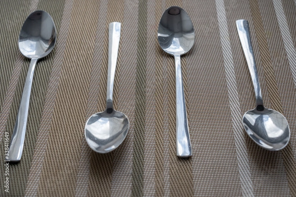 Fototapeta metal spoons are arranged on brown cloth decorated with thin brown stripes