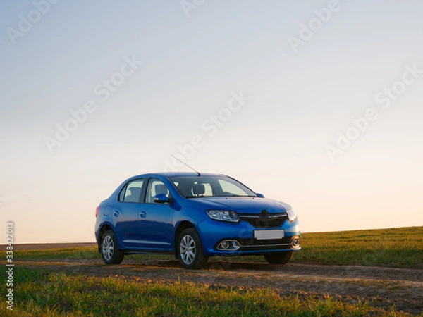 Fototapeta Belarus blue car in a field in spring at sunrise