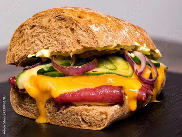 Fototapeta Big selfmade pastrami sandwich made with fresh pastrami, cucumber, onions and cheddar cheese
