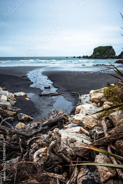 Obraz Beautiful image of a beach at low tide with wet rocks in the foreground taken on a cloudy winter day in Cape Fouldwind, New Zealand