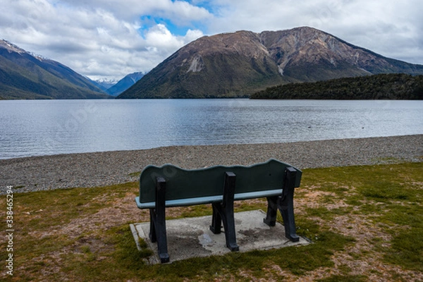 Obraz Gorgeous photo of Rotoiti Lake with a bench in the foreground and snow capped mountains in the background taken on a cloudy winter day, New Zealand