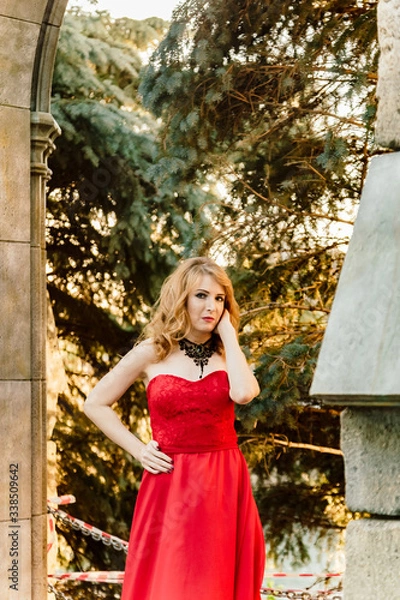 Obraz A woman in a red dress stands on a background of a medieval castle