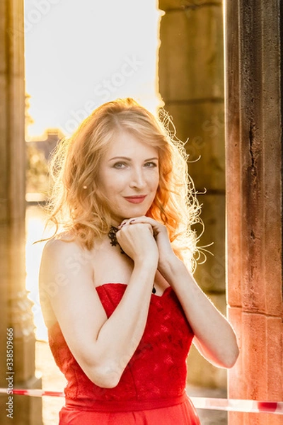 Obraz A woman in a red dress stands on a background of a medieval castle