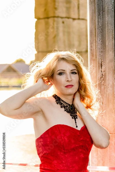 Obraz A woman in a red dress stands on a background of a medieval castle