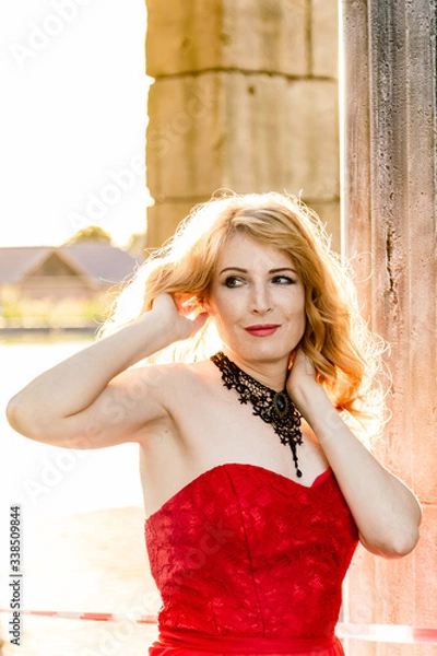 Obraz A woman in a red dress stands on a background of a medieval castle