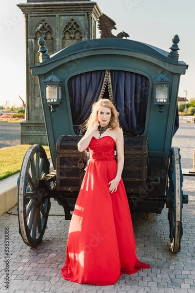 Obraz A woman in a red dress stands on a background of a medieval castle