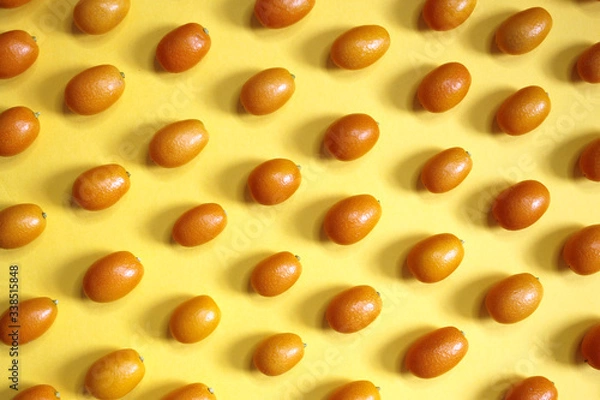 Fototapeta kumquat Fruit with half isolated on Yellow background. A Summer Background with  Fruit known as Chinese mandarin or kingen of orange color, very similar to an orange but much smaller