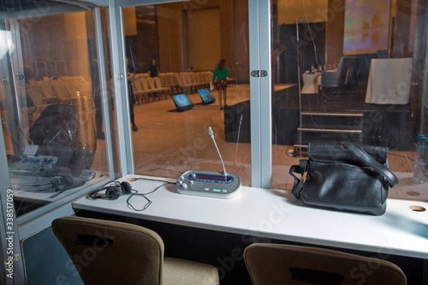 Obraz Soft focus of wireless Conference microphones and notebook in a meeting room. translators cubicle . interpreting - Microphone and switchboard in an simultaneous interpreter booth .