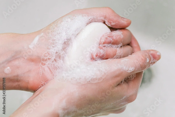 Fototapeta Woman uses soap and washes her hands under a faucet. Hygiene and hand cleaning. Prevention and control of coronavirus.