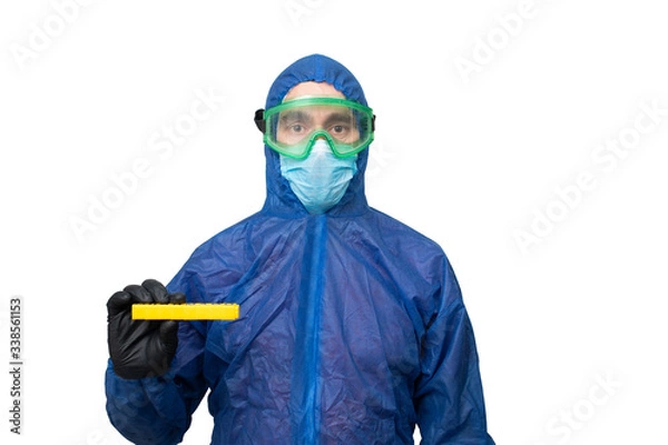 Obraz a man in a protective blue suit and mask holds a yellow sign