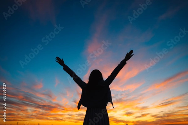 Fototapeta Woman open arms under the sunset. Concept of happy life, freedom.